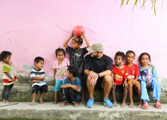Voyageur assis au côté d'enfants à Flores.
